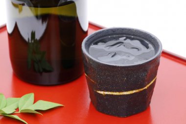 Japon Shochu şişesi ve seramik kase tahta tepside, beyaz arka planda. 