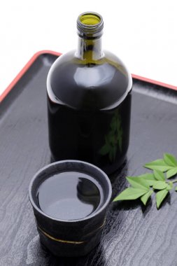 Japon Shochu şişesi ve seramik kase tahta tepside, beyaz arka planda. 