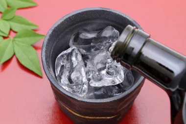 Kırmızı arka plan üzerinde Japon shochu ve seramik kase Şişe