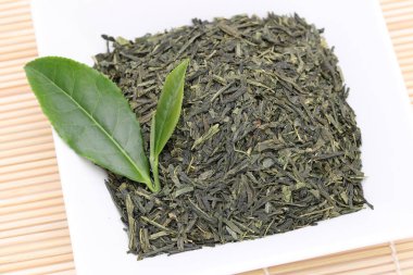 Bambu arka plan üzerinde yeşil çay yaprakları ile kurutulmuş çay yaprakları 