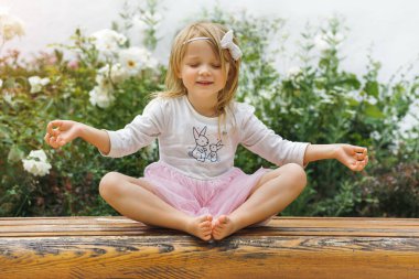 Yoga yapan küçük kız yeşil poz veriyor.