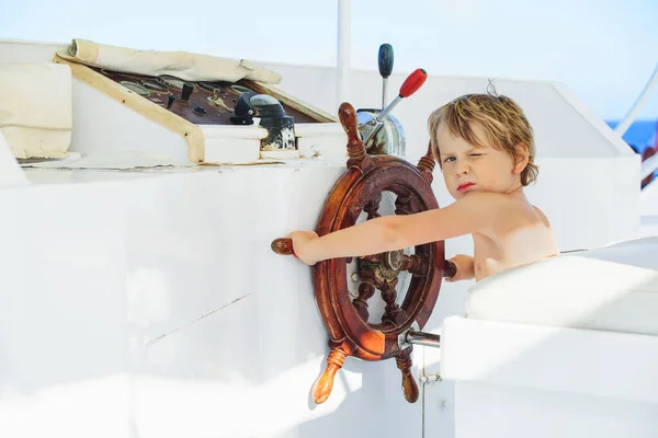 a child as a captain on the ship\'s steering wheel ready to start