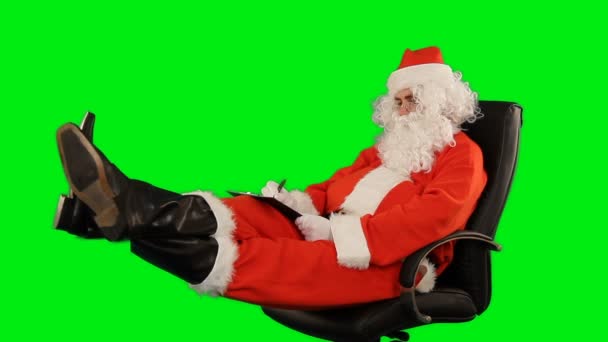 Санта Клаус Сидит Кожаном Стуле Пишет Планшете Зеленый Экран Chromakey — стоковое видео
