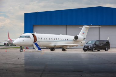 DOMODEDOVO, MOSCOW, RUSSIA - JUNE 03, 2016: Private business Jet airplane with Mercedes Benz V-class luxury car with tuning kit of Larte Design Tuning Company shown together at international airport clipart