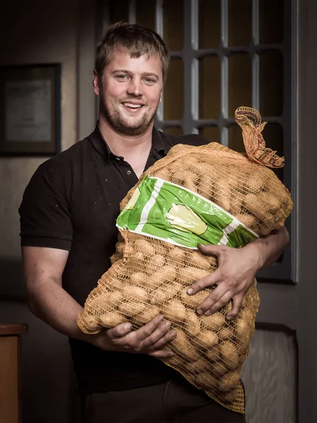 A man with a bag of potatoes. Young farmer holding a sack filled with potatoes. Niedersachsen. Saxony. Potato production and distribution in Germany
