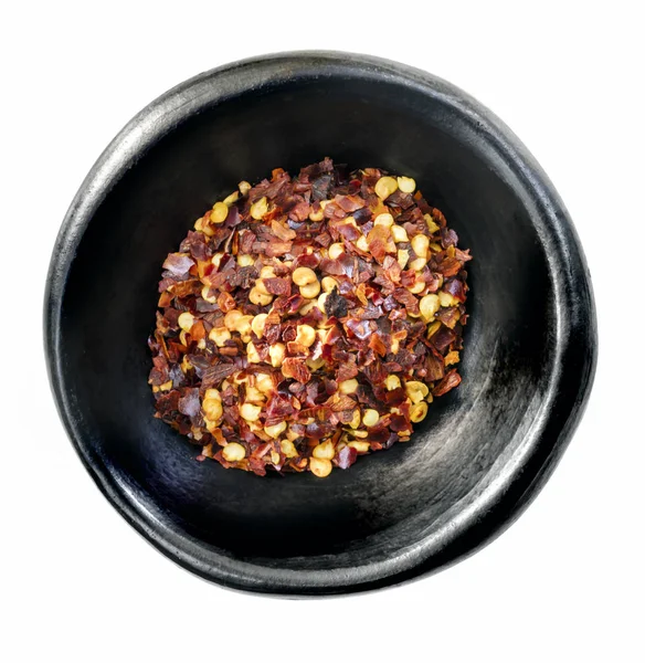 Hot chilli płatki w czarnej Bowl izolowane na białym Top View — Zdjęcie stockowe