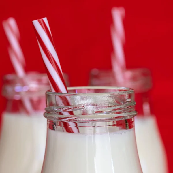 Latte Bottiglie Vetro Con Cannucce Strisce Rosse Bianche Fondo Rosso — Foto Stock