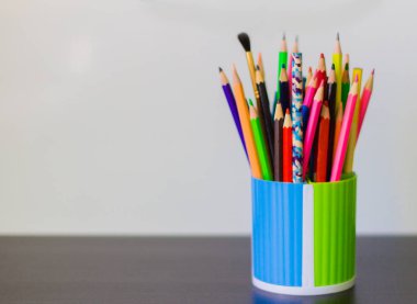 renkli kalemler ve Kalem masanın üzerine bir bardak