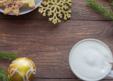  bir fincan kahve ile kalın köpük, şeker ve tarçın ve Noel süslemeleri ile Noel tatlılar