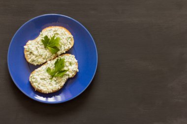 süzme peynir ve mavi bir plaka üzerinde otlar ile sandviç