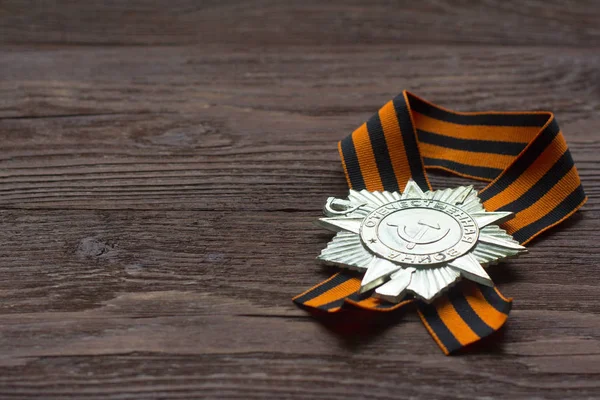 Victory symbol, St. George ribbon and order on wooden background