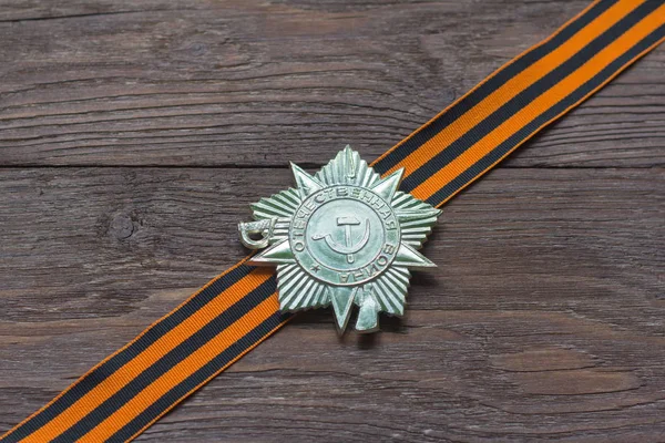 Victory symbol, St. George ribbon and order on wooden background