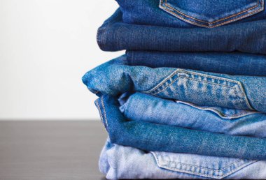 masanın üzerinde farklı tonları mavi kot yığını