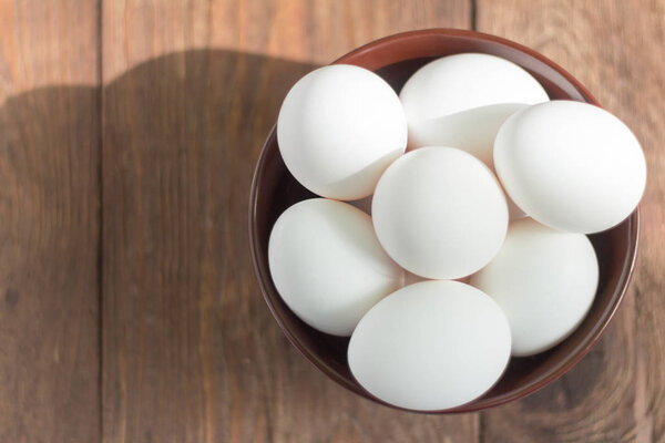 white chicken eggs in bowl on wooden background