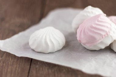 lezzetli tatlı, ahşap arka plan üzerinde beyaz kağıt üzerinde hassas beyaz ve pembe marshmallow