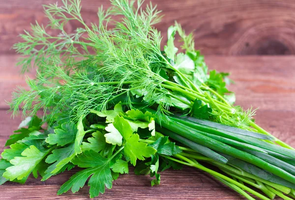 fresh greens, dill, parsley and green onions on wooden background.bunch of fresh herbs