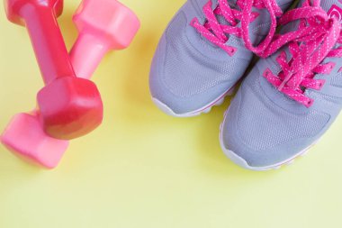 açık sarı arka plan, sağlıklı yaşam tarzı, metin için alan parlak pembe bağcıklar ve pembe dambıl ile spor gri spor spor