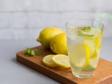 limon ve kekik yaprakları, ısıtmaya susuzluğunu gidermek ve sesi korumak için serinletici bir alkolsüz içecek ile bir cam su