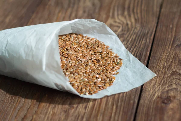 flax seeds in paper bag on wooden background