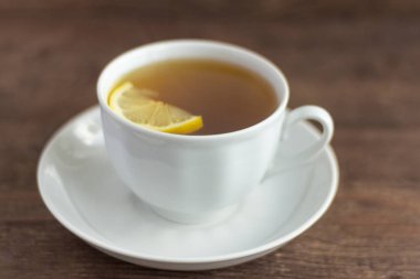 ahşap bir arka plan üzerinde limon bir dilim ile bitkisel çay bir Fincan
