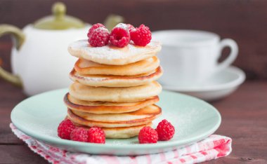 ahududu ile pişmiş ev yapımı krep yığını, arka planda toz şeker ve çay eşyaları ile serpilir, seçici odak