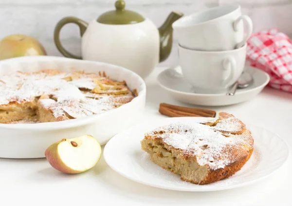 Домашний яблочный пирог с корицей и посудой для чая на столе — стоковое фото