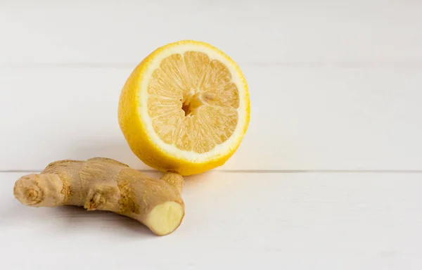 Fresh lemon and ginger root on light wooden background