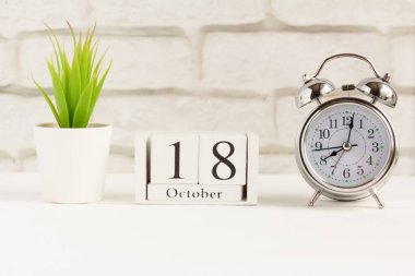 18 Ekim 'de, çalar saatin yanındaki ahşap takvimde, sonbahar ayının tarihi..