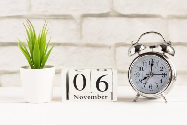 Alarm saatinin yanındaki ahşap takvimde geçen sonbahar ayının takvim tarihi var.