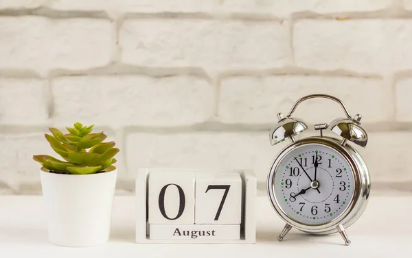7 Agustus pada kalender kayu di sebelah jam alarm. Hari musim panas, ruang kosong untuk teks .Calendar untuk Agustus pada latar belakang cahaya. — Stok Foto