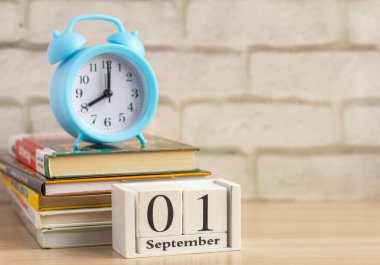 Takvimde 1 Eylül 'de okula döneceğim. Alarm saati ve masanın üzerinde bir yığın ders kitabı.