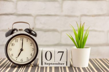 7 Eylül 'de alarm saatinin yanındaki ahşap takvimde. Emeklilik günü, metin için boş alan. Eylül ayı takvimi hafif arkaplan üzerine.