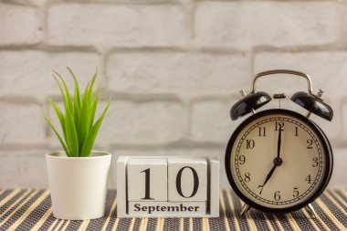 10 Eylül 'de alarm saatinin yanındaki ahşap takvimde. Emeklilik günü, metin için boş alan. Eylül ayı takvimi hafif arkaplan üzerine