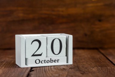 Takvime göre 20 Ekim. Koyu ahşap bir arka planda çalar saatin yanında. Sonbahar ayının tarihi..