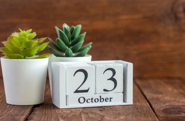 Takvimde 23 Ekim. Koyu ahşap bir arka planda çalar saatin yanında. Sonbahar ayının tarihi.