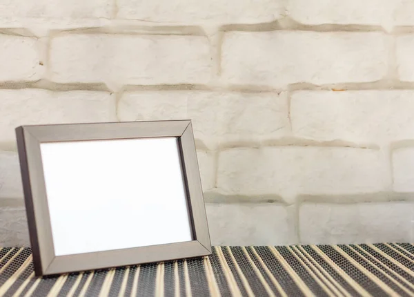 An empty photo frame in a dark frame on a table or shelf with a copy of the place