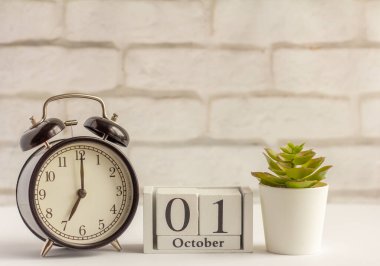 1 Ekim. Alarm saatinin yanındaki ahşap takvimde. Sonbahar ayının bir günü kavramı..