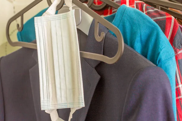 A protective surgical mask hangs on a clothes rack.Protection from viruses and infections when leaving the house.Element of the wardrobe.