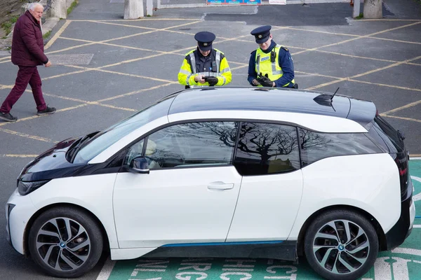 İrlanda, Dublin, 03 / 19 / 2020, Polis BMW elektrikli aracına elektrikli benzin istasyonunda yanlış park ettiği için ceza kesti..