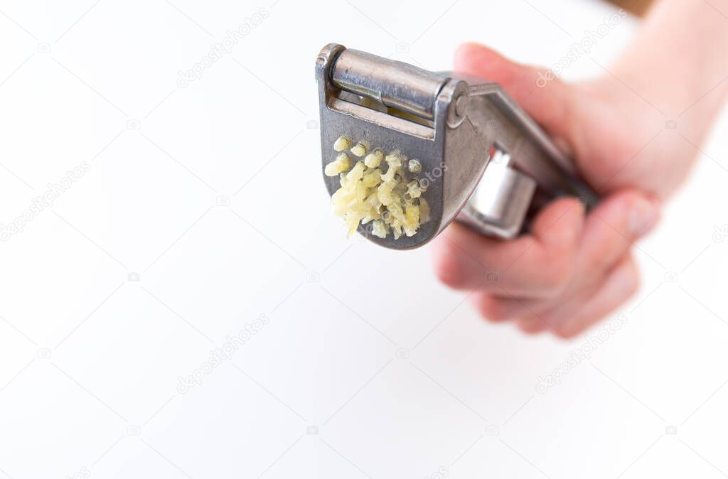 Male hands hold a garlic press or garlic squeezer. Kitchen Tool for preparing and preparing salads, dishes.