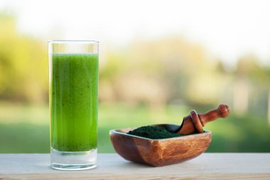 Ahşap masa üzerinde spirulina ile yeşil smoothie