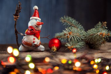 Noel kardan adam, çam ağacı, garland ve önemsiz şey ahşap masa üzerinde gülümseyen