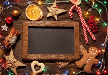 gingerbread Noel dekorasyonları ahşap masa, üstten görünüm üzerinde çerçeve içinde boş yazı tahtası