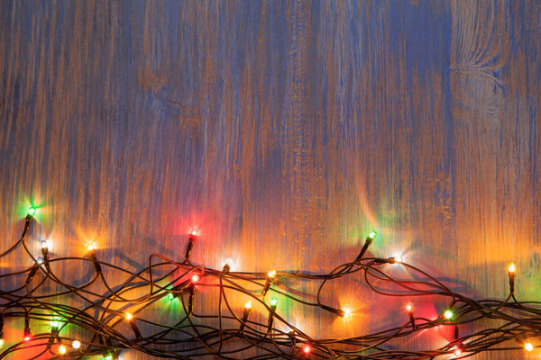 christmas celebration garland with light bulbs on wooden background with copy space for inscriptions