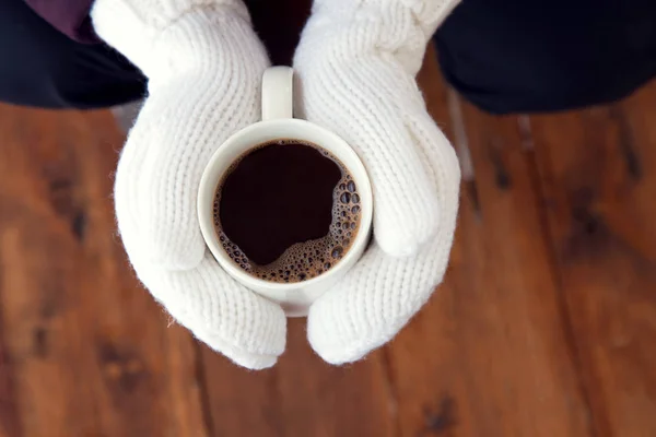 coffee cup in hands in white mittens outdoor in the winter on Christmas Eve, top view