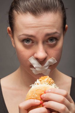 Diyet kavramı: hamburger ile ağız kapalı tutan kadın