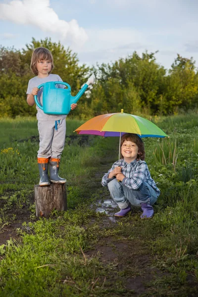 Dos hermanos juegan bajo la lluvia al aire libre — Foto de Stock