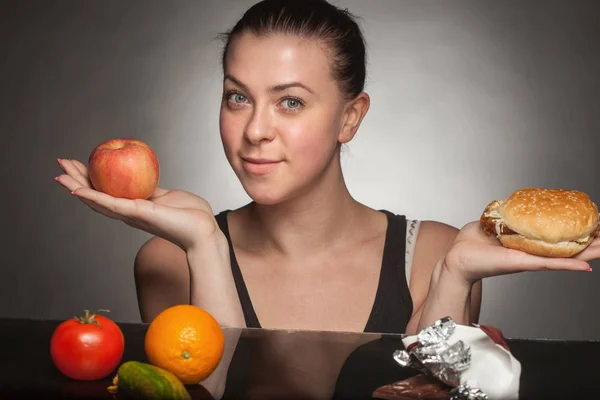 Concepto de dieta: mujer sosteniendo hamburguesa y manzana —  Fotos de Stock