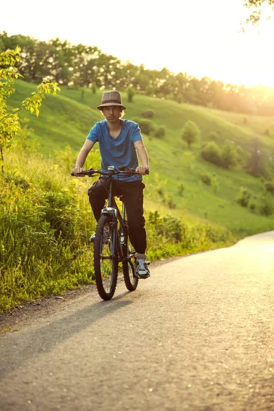 Tiener rijdt op een fiets op de weg zomer zonovergoten — Stockfoto