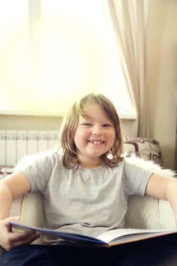 Mutlu küçük çocuk kitap okuyor, güneşli bir günde.